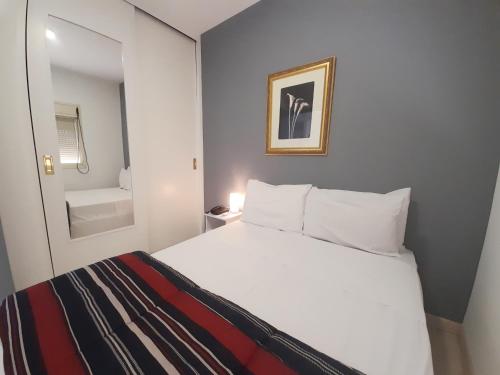 a bedroom with a white bed and a bathroom at Flat INCRIVEL na Vila Olimpia in Sao Paulo