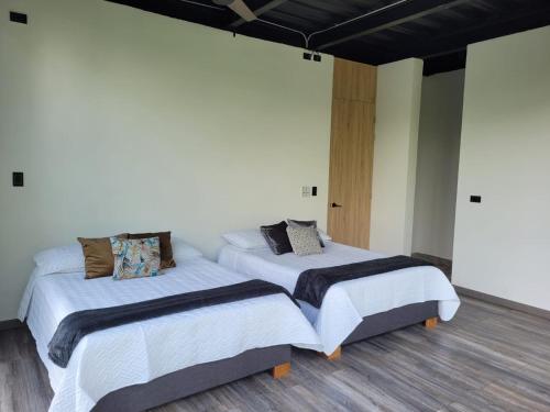 two beds in a room with white walls and wood floors at MILAVES in La Tebaida