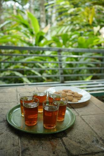 a tray with four glasses of tea and a plate of cookies at Willow Creek in Wayanad