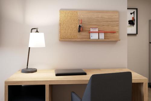 a wooden desk with a lamp and a book at Candlewood Suites Murfreesboro by IHG in Murfreesboro
