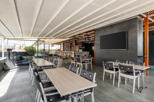 a restaurant with tables and chairs and a flat screen tv at Hotel 100 Luxury Suites by Preferred in Bogotá