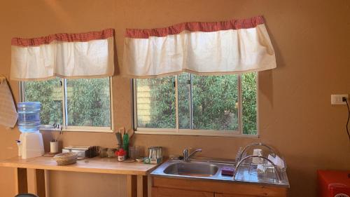 a kitchen with two windows and a sink at Cabañas Guanaqueros Arriendo Diario in Guanaqueros