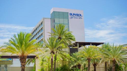 um edifício com palmeiras em frente em SUNSOL UNIK Luxury Hotel em Porlamar