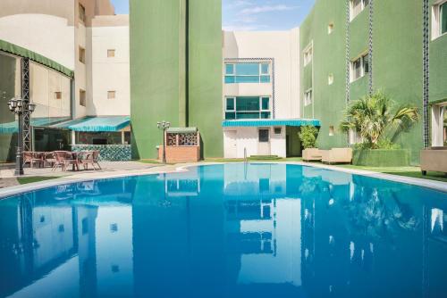 a swimming pool in front of a building at Ramada by Wyndham Dammam Khaleej Road in Dammam