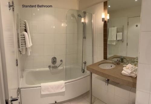 a bathroom with a bath tub and a sink at Bedford Lodge Hotel & Spa in Newmarket