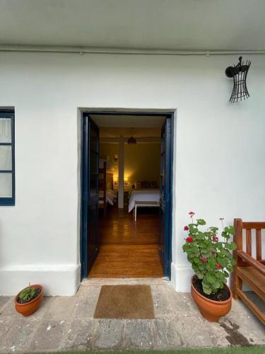 an open door of a white house with two plants at Illa B&B in Cusco