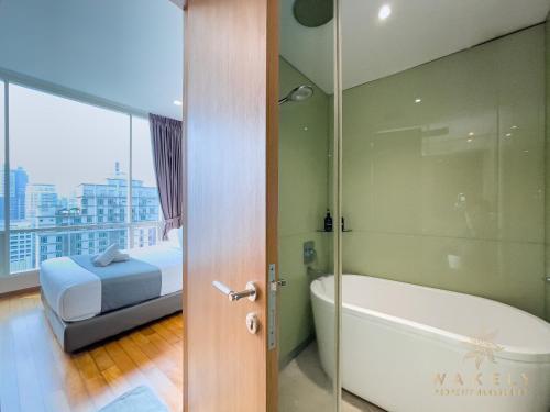 Soho Suites KLCC by Wakely Kuala Lumpur في كوالالمبور: حمام مع حوض وسرير وباب زجاجي