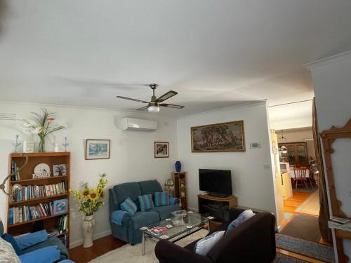 a living room with a blue couch and a ceiling fan at La Casa Della Nonna in Australia in Lakes Entrance