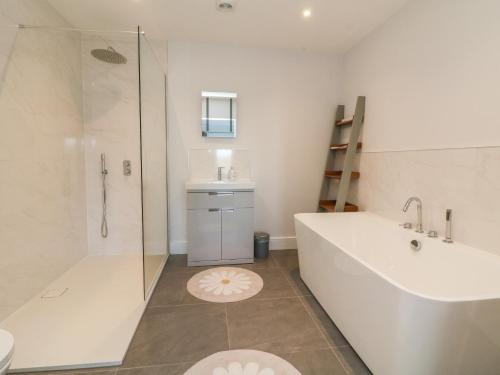 a bathroom with a tub and a shower and a sink at Linden View in Ilfracombe