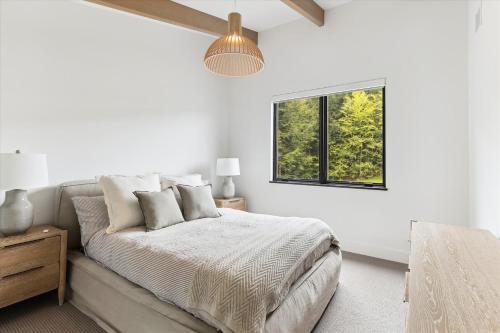 a white bedroom with a bed and a window at Streamside Lodge in Stowe