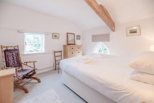 a bedroom with a large white bed and a chair at The Old Chapel, Wissett in Halesworth