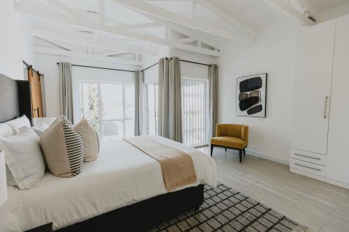 - une chambre blanche avec un lit et une chaise dans l'établissement Stunning Luxury Villa Home with breathtaking views!, à Helensvale