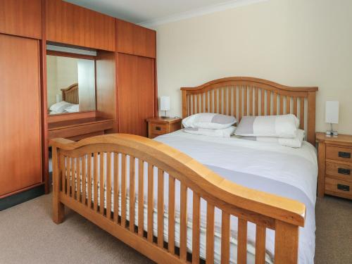1 dormitorio con cama de madera y espejo en Dunira, en Mallaig