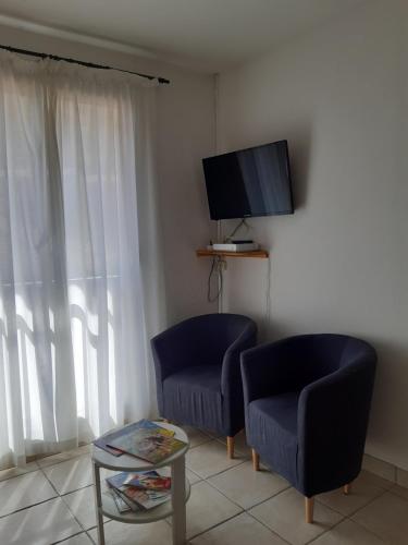 - un salon avec deux chaises, une télévision et une table dans l'établissement Studio meublé deux étoiles à DIGNE LES BAINS, à Digne-Les-Bains