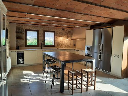 a kitchen with a large wooden table and a refrigerator at La Creu de la Pinya in Berga