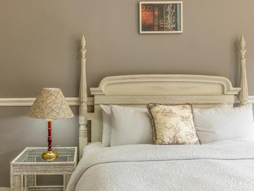 a bedroom with a white bed and a lamp at Pousada Parador Santarém in Itaipava