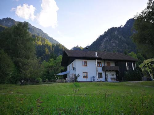 a white house with a black roof in a field at Ferienwohnung Achselkopf in Musau