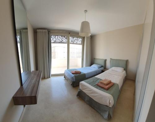 a bedroom with two beds and a window at Mangroovy 2BR with roof in Hurghada