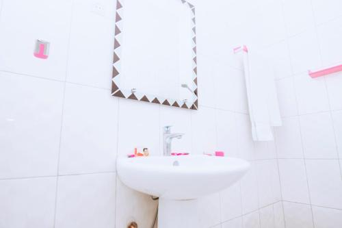 a white bathroom with a sink and a mirror at Peace Guest House in Muhari