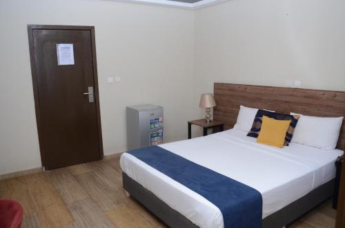 a bedroom with a large bed with a wooden headboard at BLUEBAY HOTEL ABIDJAN in Abidjan