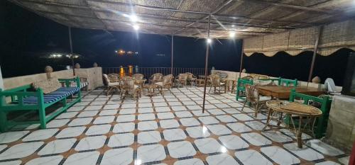 Meshra Katto في أسوان: غرفة بها طاولات وكراسي على أرضية من البلاط