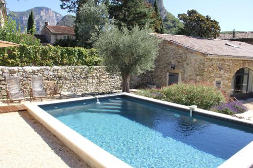 una piscina en un patio con una pared de piedra en Gîte Les Oliviers, en Saou
