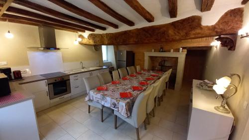 uma cozinha com uma mesa longa com cadeiras e uma cozinha com uma mesa; em Maison Anjou 13 personnes em Montreuil-Bellay