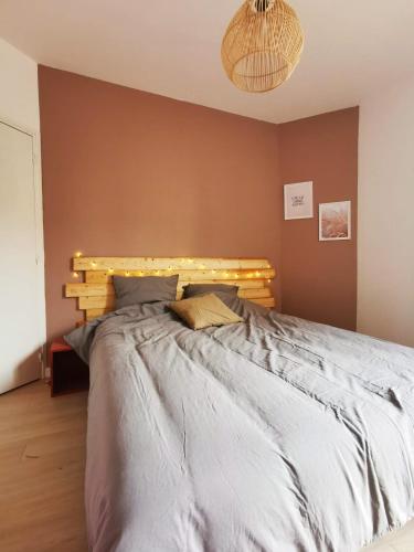 een slaapkamer met een groot bed met een houten hoofdeinde bij Le Bohème (Centre - Gare - Commerces) in Lens