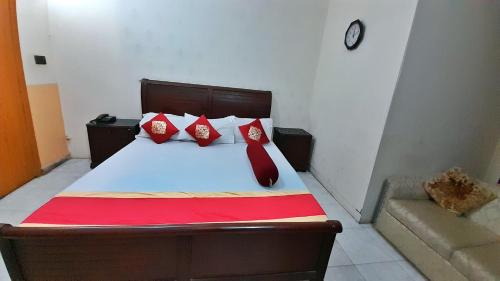 a bedroom with a bed with red pillows and a clock at Hotel Super Seven in Lahore