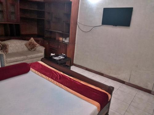 Hotel Super Seven في لاهور: غرفة بسرير واريكة وتلفزيون