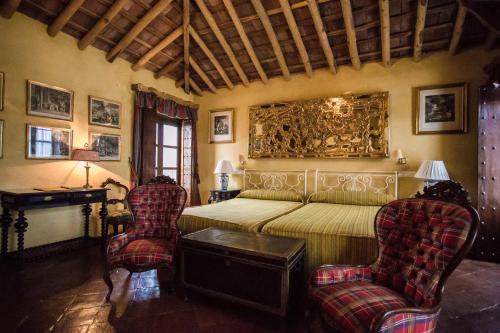 Un dormitorio con una cama y dos sillas. en El Palacio de San Benito, en Cazalla de la Sierra