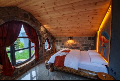 a bedroom with a bed in a stone wall at Hobbit Chalet in Çamlıhemşin