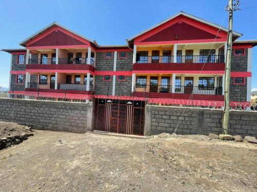 a red building with a fence in front of it at Dzefry Homes in Nakuru