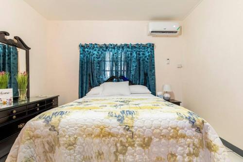 a bedroom with a large bed with a blue curtain at Shaw Park Gem in Ocho Rios