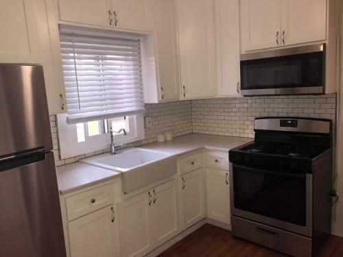 a kitchen with white cabinets and a sink and a stove at Urban Oasis with Private Laundry: Steps from DTLA in Los Angeles