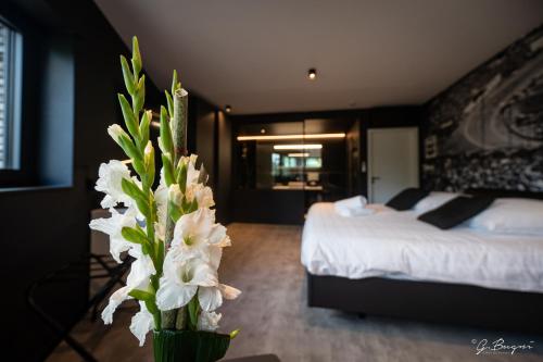 a bedroom with a bed and a vase with white flowers at Les Thermes de Spa by La Cour de la Reine Hôtel, Suites & accès gratuit au centre thermal in Spa