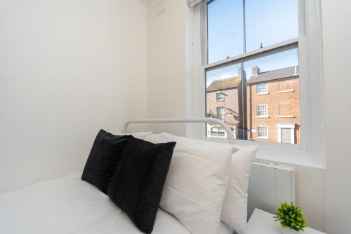 a white bed with black pillows in front of a window at Central Two Bed Flat Kings Lynn in King's Lynn