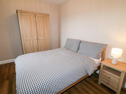 Schlafzimmer mit einem Bett mit einer schwarzen und weißen Bettdecke und einem Schrank in der Unterkunft Rose Cottage in Omagh