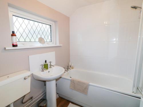 een badkamer met een wastafel, een bad en een toilet bij Rose Cottage in Omagh