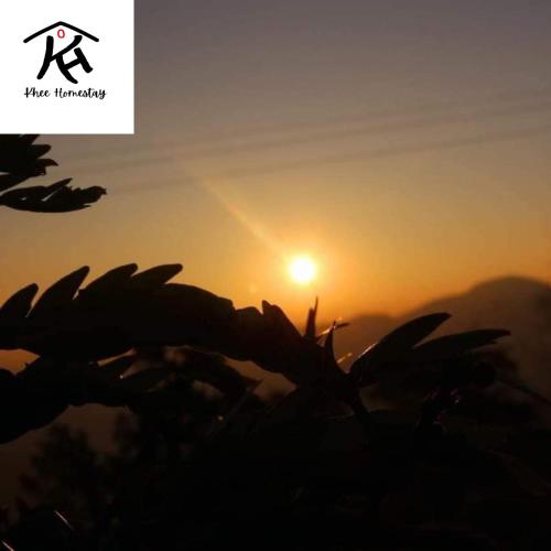 a silhouette of a sun setting over a field at Khee Homestay in Kurseong