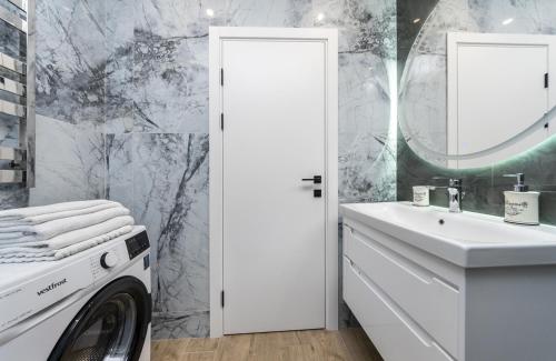 ein weißes Badezimmer mit einer Waschmaschine und einem Waschbecken in der Unterkunft Luxury apartment near metro station Osokorky in Kiew
