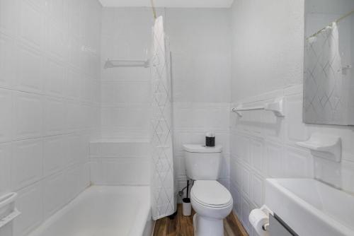 a white bathroom with a toilet and a bath tub at Seascape - Mins to Las Olas & Beach in Fort Lauderdale