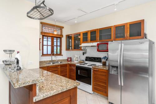 a kitchen with a stainless steel refrigerator and wooden cabinets at Villa del Sueño in Playa Hermosa
