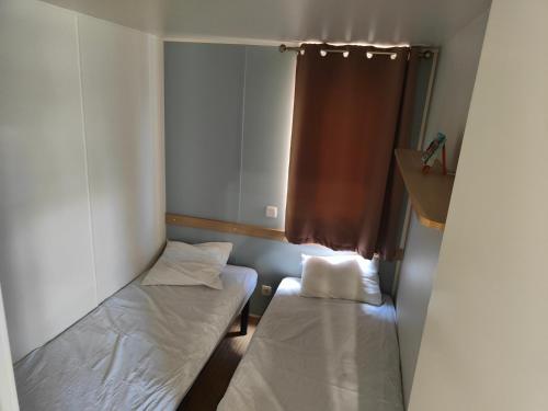 une petite chambre avec deux lits et une fenêtre dans l'établissement Mobil-home, à Valras-Plage