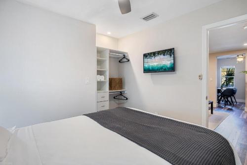 a white bedroom with a white bed and a desk at Horizon - Mins to Las Olas & Beach in Hammocks