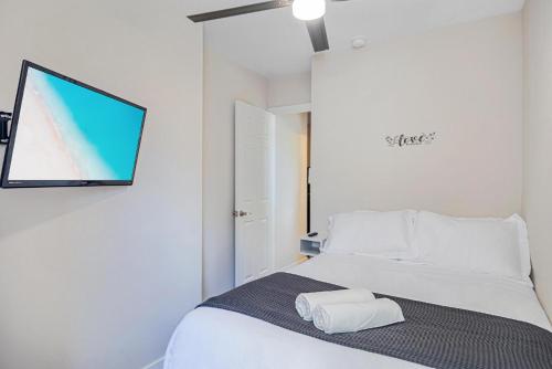 Schlafzimmer mit einem Bett und einem TV an der Wand in der Unterkunft Horizon - Mins to Las Olas & Beach in Hammocks