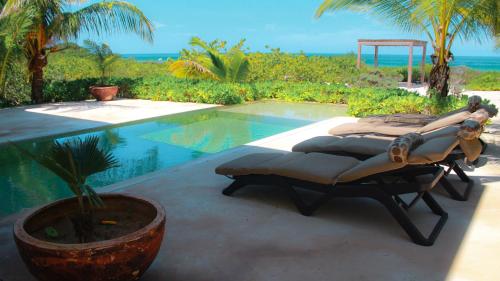 a couple of beds sitting next to a swimming pool at Donoussa Beach home in Uaymitun