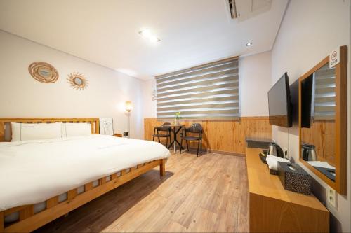 a bedroom with a bed and a tv and a table at Sea Star Hostel in Yeosu