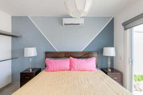 1 dormitorio con 1 cama grande con almohadas rosas en Villa Alberca Privada 10 pax, en Cabo San Lucas