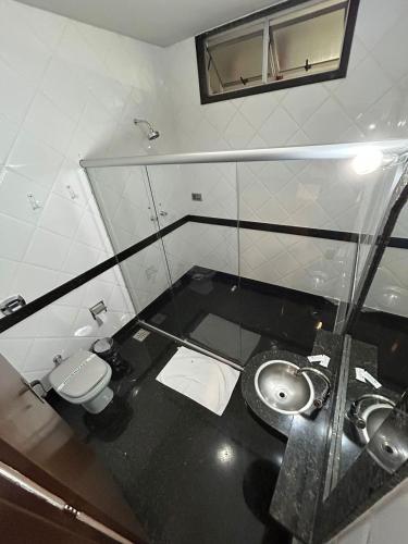ein Badezimmer mit einem Waschbecken, einem WC und einem Spiegel in der Unterkunft Motel Ibiza in Pará de Minas